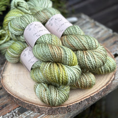 Five skeins of green yarn with washes of brown and yellow