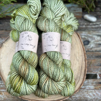 Five skeins of green yarn with washes of brown and yellow