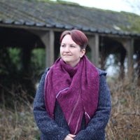 Victoria wearing a purpley pink triangular shawl wrapped around her neck. The shawl has stripes in muted contrast colours