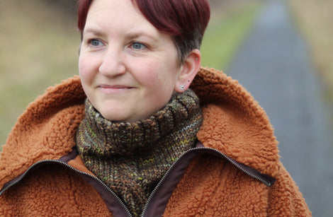 Victoria wearing a brown fleece and a variegated brown cowl with a single cable up the front.
