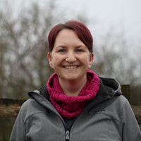 Victoria wearing a grey jacket and a bright pink cowl with a single cable up the front.
