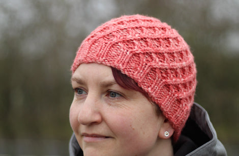 Victoria wearing a pink beanie hat with a lattice cable design