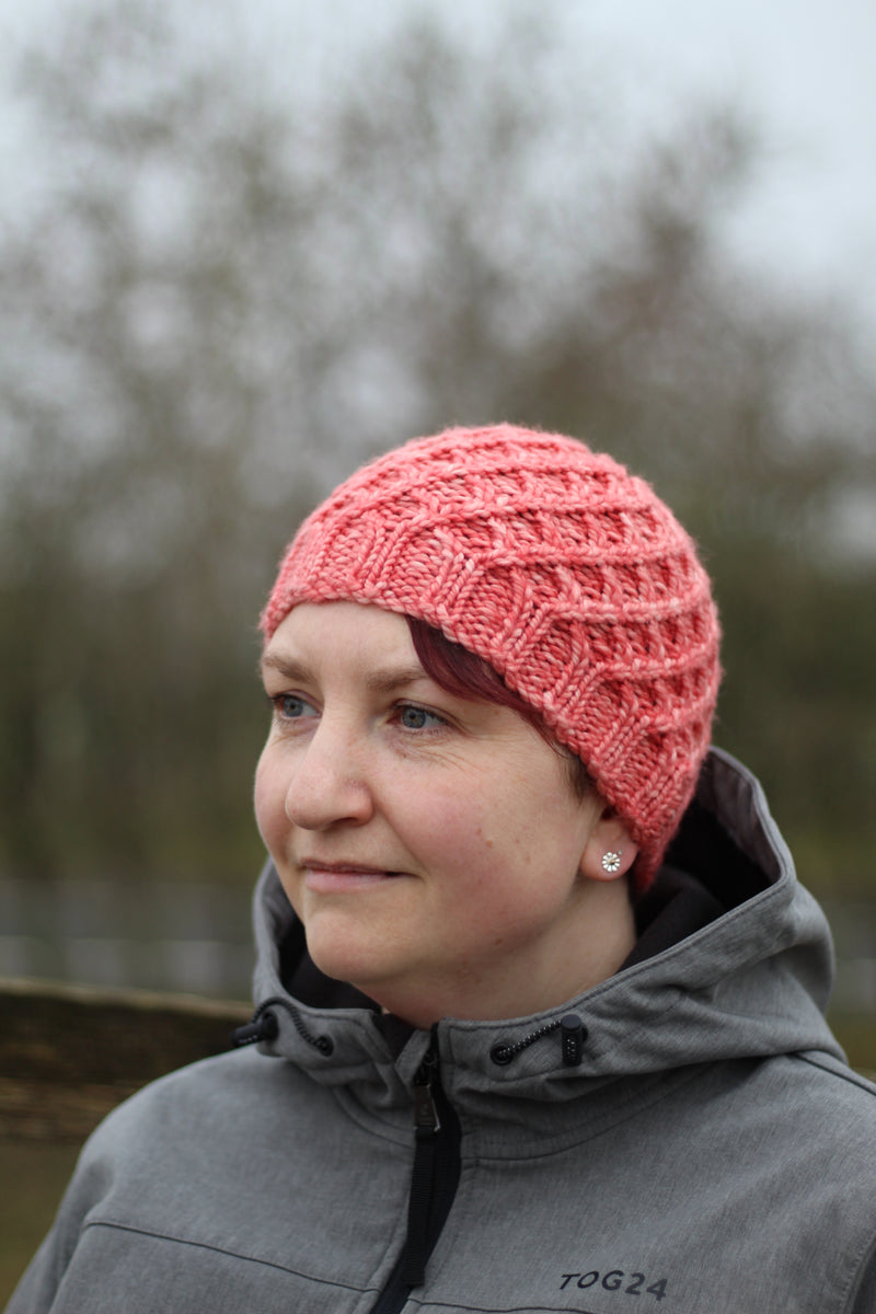 Victoria wearing a pink beanie hat with a lattice cable design
