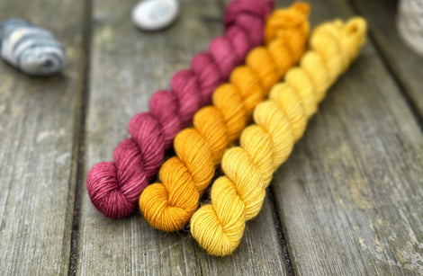 Three mini skeins of yarn in shades of red and yellow