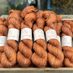 Skeins of orangey brown yarn with white linen slubs running through them