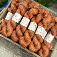 Skeins of orangey brown yarn with white linen slubs running through them