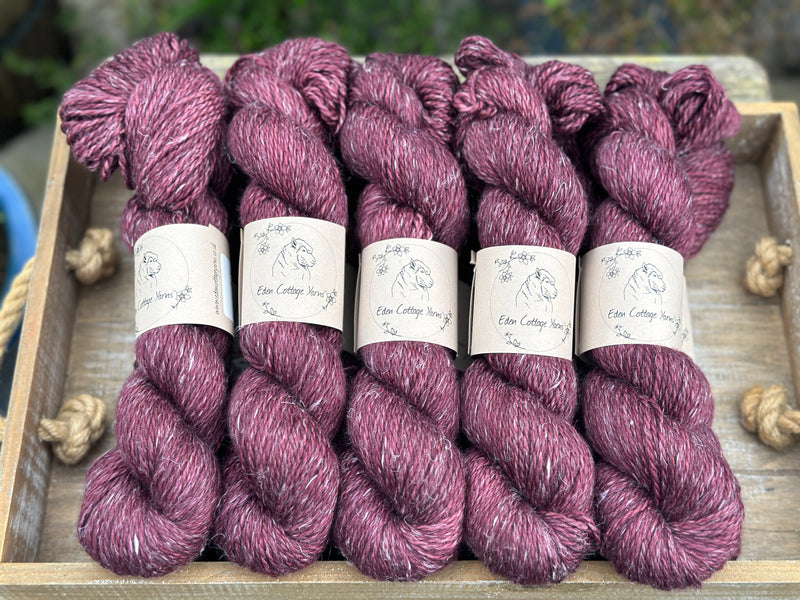 Skeins of dark purple yarn with white slubs running through them