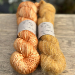 Two skeins of orange yarn, one is a fluffy laceweight skein