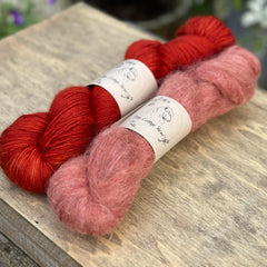 Two skeins of red yarn - one is a fluffy laceweight skein.
