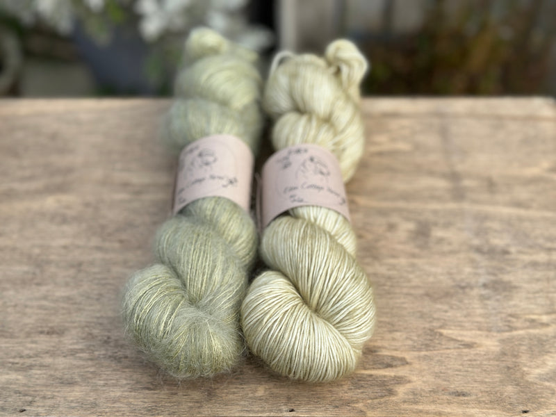 Two skeins of green yarn - one is a fluffy laceweight skein.