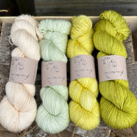 Four skeins of yarn in shades of green