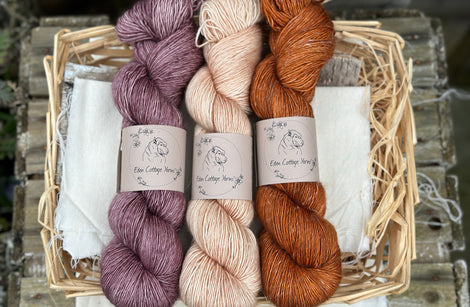 Three skeins of yarn. From left to right: a purple skein, a pale orange skein and an orangey brown skein