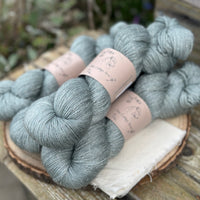 Four skeins of grey yarn with silver sparkle running through it