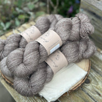 Four skeins of grey-brown yarn with silver sparkle running through it