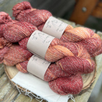 Five skeins of variegated red and gold yarn with silver sparkle running through it