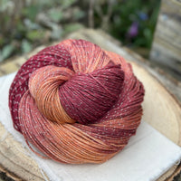 A swirl of variegated red and gold yarn with silver sparkle running through it