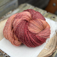 A swirl of variegated red and gold yarn with silver sparkle running through it