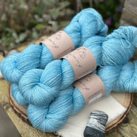 Five skeins of bright blue yarn with silver stellina running through it