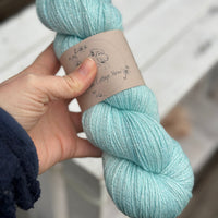 One skein of pale blue yarn with silver stellina running through it