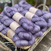 A wicker basket containing several skeins of purple yarn