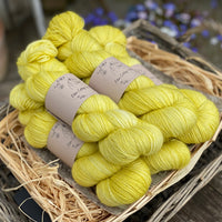 Five skeins of bright yellowy green yarn with gold sparkle running through it