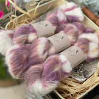 Three skeins of variegated purple, pink, orange and cream fluffy yarn