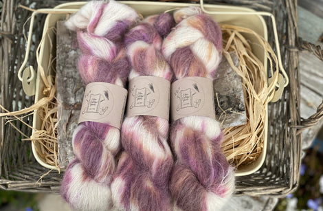 Three skeins of variegated purple, pink, orange and cream fluffy yarn