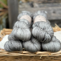 Five skeins of grey yarn with black speckles