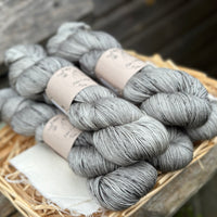 Five skeins of grey yarn with black speckles