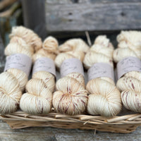 Five skeins of yellowy beige yarn with reddish-brown speckles