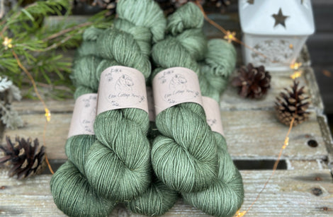Five skeins of green yarn with fine gold fibres running throughout