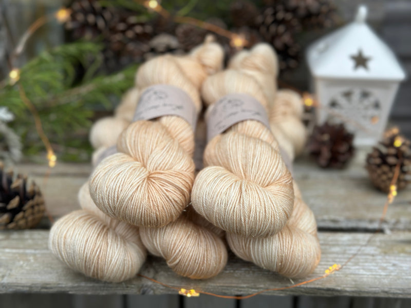 Five skeins of beige yarn with fine gold fibres running throughout