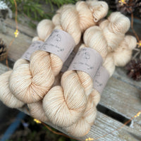 Five skeins of beige yarn with fine gold fibres running throughout