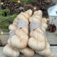 Five skeins of beige yarn with fine gold fibres running throughout 