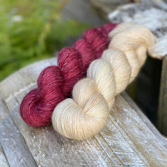 Two skeins of yarn - one purpley-red and one cream