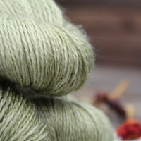 Close up image of green skeins of yarn showing strands of linen spun into it