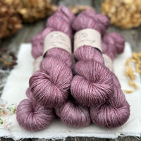 Five skeins of purple yarn with white threads throughout