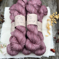 Five skeins of purple yarn with white threads throughout