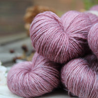 Close up image of purple yarn with white strands of linen spun throughout