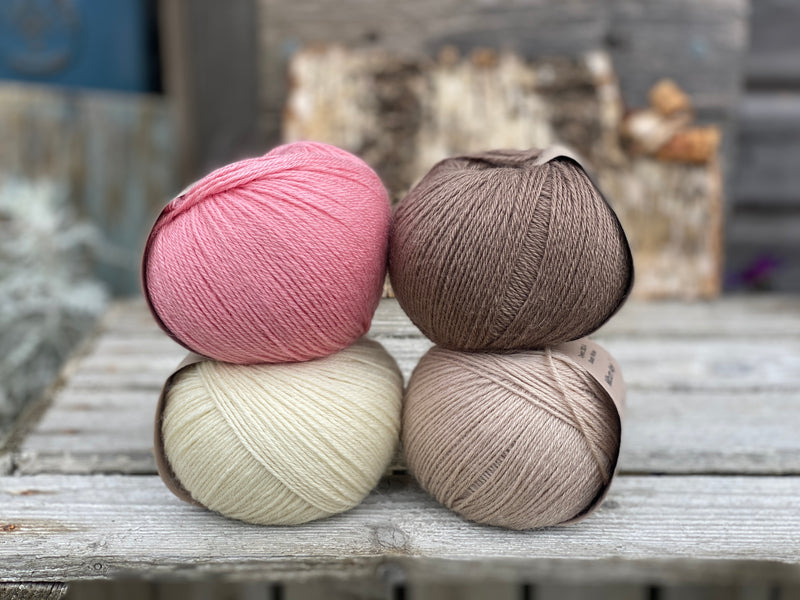 Four balls of yarn. Colours are natural cream, beige, pink and brown