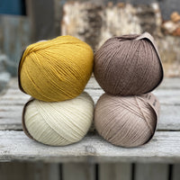 Four balls of yarn. Colours are natural cream, beige, yellow and brown