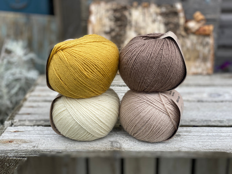 Four balls of yarn. Colours are natural cream, beige, yellow and brown