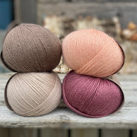 Four balls of yarn. Colours are beige, peach, purpley pink and brown
