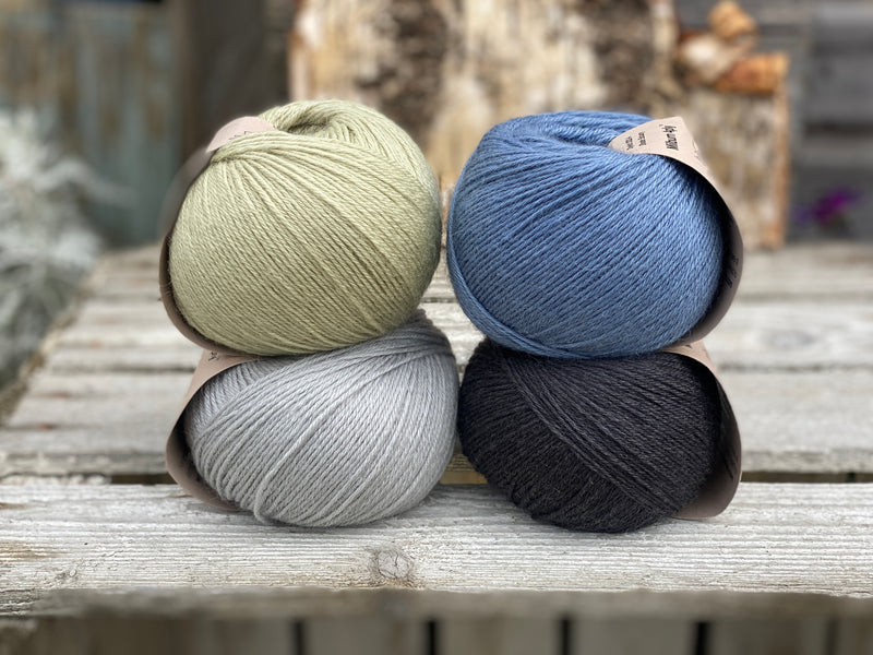 Four balls of yarn. Colours are pale blue, blue, pale green and black