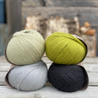 Four balls of yarn. Colours are pale blue, pale green, green and black