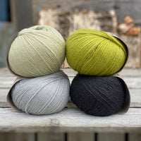 Four balls of yarn. Colours are pale blue, pale green, green and black