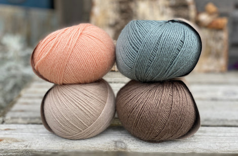 Four balls of yarn. Colours are beige, peachy orange, teal and brown