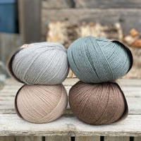 Four balls of yarn. Colours are beige, brown, teal and pale blue