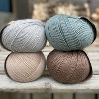 Four balls of yarn. Colours are beige, brown, teal and pale blue