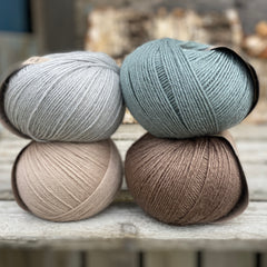 Four balls of yarn. Colours are beige, brown, teal and pale blue